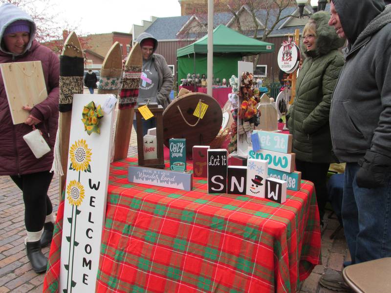 Visitors of Christmas in the Valley in Spring Valley walk by the Pallet Project by T&C vendor booth Saturday, Nov. 12, 2022. Pallet Project by T&C sells its items at Debo Ace Hardware in Peru.