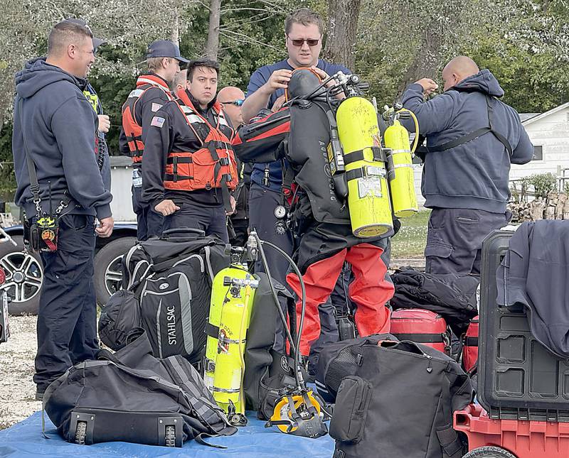 A diver prepare to search an area as divers from the Antioch Fire Protection District and a sonar team from the Illinois Department of Natural Resources continue searching Tuesday, Oct. 7, 2025, on Fox Lake near Antioch for a man thrown from a boat he was test driving Monday night.