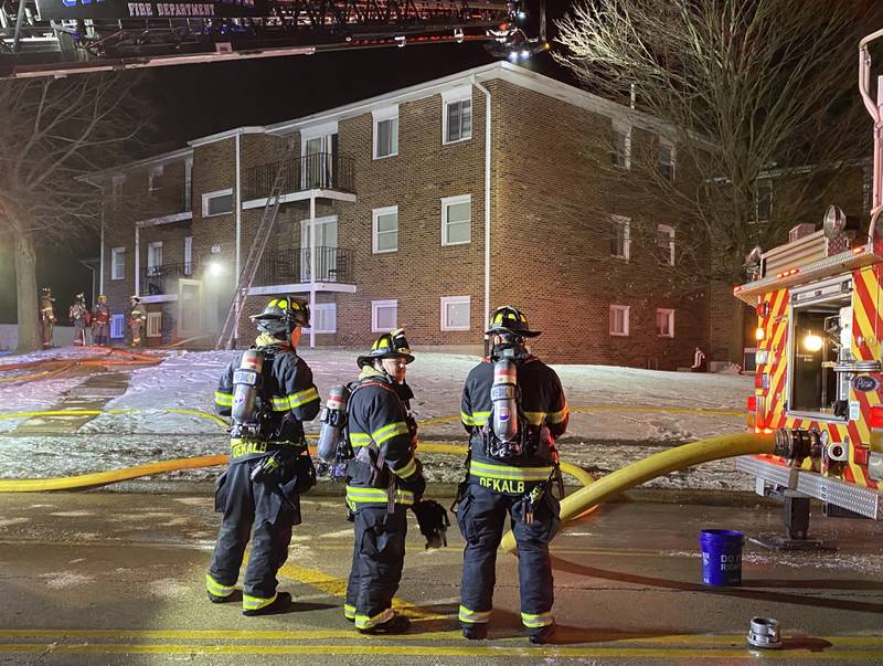 Three DeKalb firefighters stand ready to aid crews responding to an apartment fire on Sunday, Dec. 22, 2024, at 1024 W. Hillcrest Drive in DeKalb. The blaze, just before Christmas, is expected to impact multiple residents in the three-building complex.