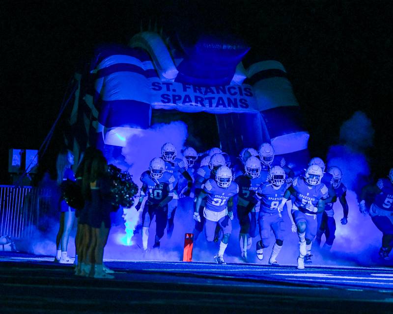 Smoke machines and a blue spotlight highlight St. Francis football team as they run onto the field before the start of their homecoming game on Friday Sep. 29, 2023, as they took on IC Prep at St. Francis in Wheaton.