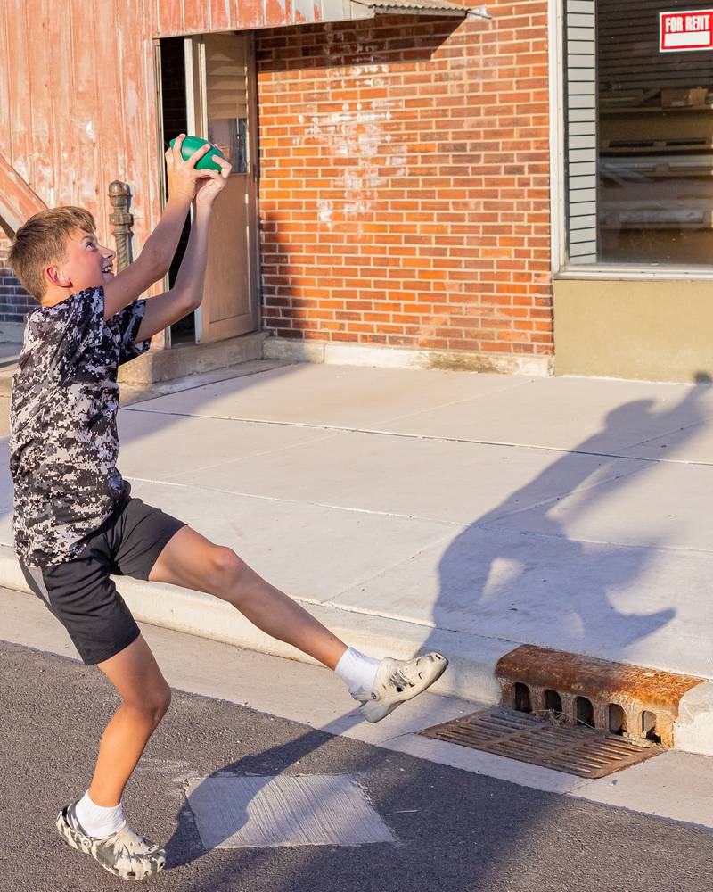 Parade spectator Jase Keegan leaps into the air to catch a pass of a foam football thrown from the Bruins varsity football team float during the St. Bede homecoming parade on October 3, 2025 in Peru.