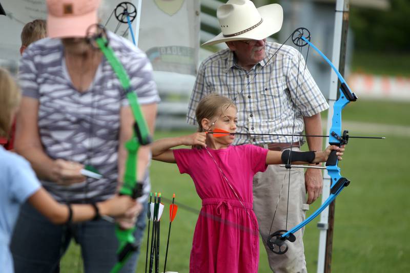 Lia Brogan, 8, visiting from Cleveland, lines up her bow and arrow with the help of Randy Rutledge of Illinois Target Archery during the DuPage County Fair in Wheaton on Friday, July 29, 2022.