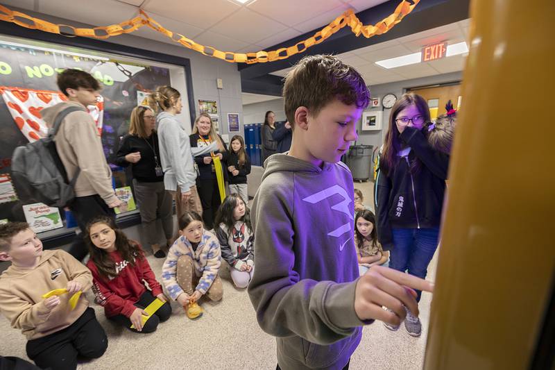 Lincoln School fifth grader Marshall chooses a book Tuesday, March 25, 2025, from a new vending machine. Students can buy book tokens with Warrior Bucks, credits earned through positive behavior.
