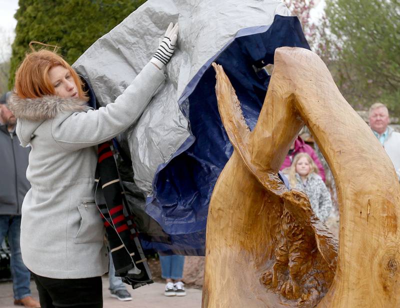 Director of Village Affairs Jamie Turczyn unveils a wood carving by Wooden Matter Carving Company during the 20th anniversary of the tornado at the memorial on Saturday, April 20, 2024 in Utica.