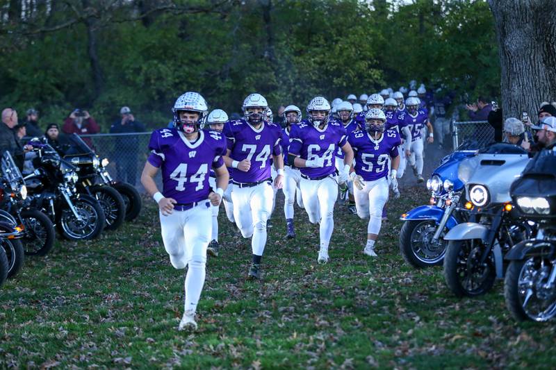 The Wilmington football team runs into the stadium during Class 2A semi-final playoff football game between Moroa-Forsyth at Wimington.  Nov 18, 2023.