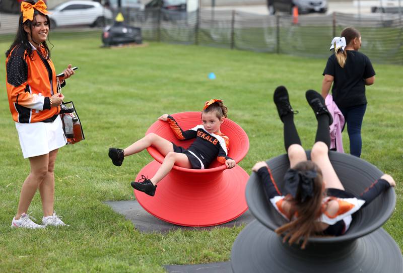 Jessica Baley-Simon watches her daughters Victoria, (left) 6, and Scarlett Simon, 8, from Malta, play on the tops Friday, Aug. 29, 2025, at the cookout before the Sycamore and DeKalb football game in the FNBO Challenge at Northern Illinois University.
