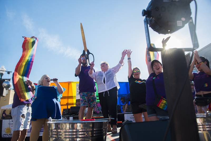Joan Sheridan raises high the scissors after cutting the ribbon as the grand marshal of Dixon’s Pride Fest. Sheridan is mother to organizer Andrew Glasscock’s (left) husband.