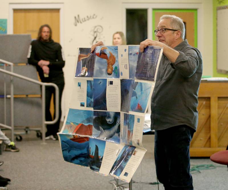 Children's author David Biedrzycki holds how a children's book is printed on a printing press before being bound into a book during a interactive presentation to students on Tuesday, March 21, 2023 at JFK School in Spring Valley.