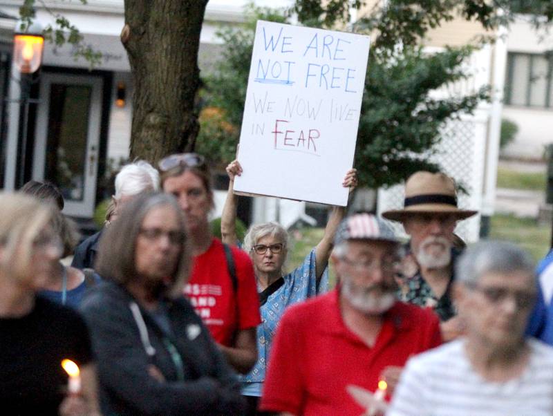 Abby Ehrhardt of Geneva (center) holds a sign up during a candlelight vigil Wednesday, July 6, 2022, at the Kane County Courthouse in Geneva. The vigil was called to join in solidarity in honor of the mass shooting at a Fourth of July parade in Highland Park.
