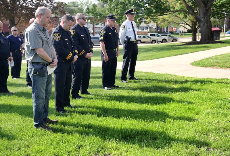 Area law enforcement members bow their heads as Taps is played honoring fallen officers from the past year Friday, May 13, 2022, at the DeKalb County Law Enforcement Officers' Memorial Service on the lawn of the DeKalb County Courthouse in Sycamore.
