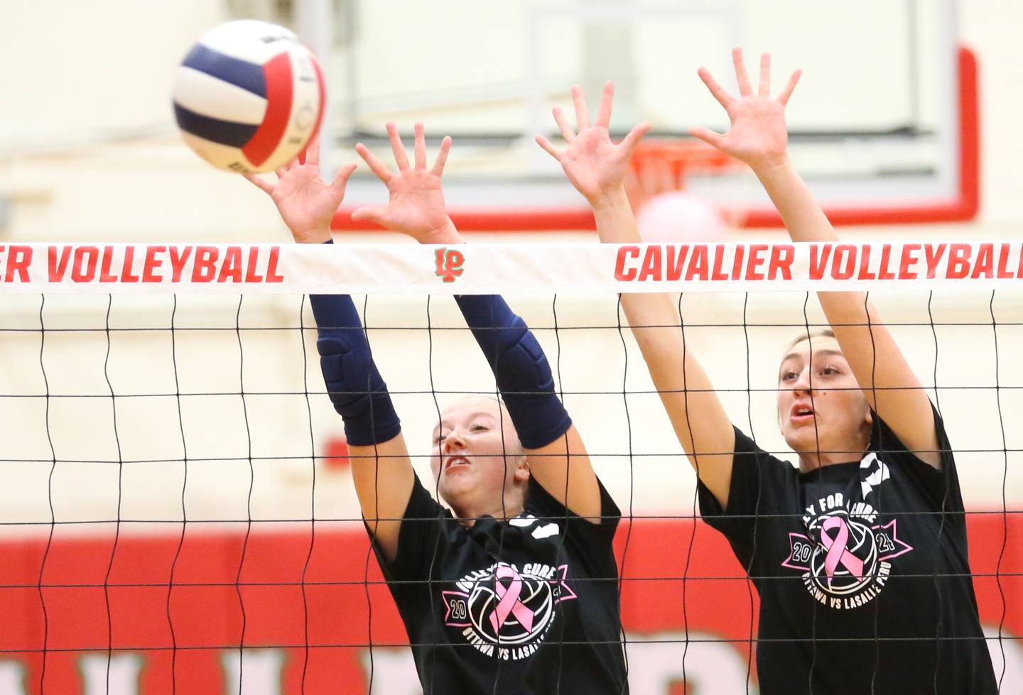 Ottawa's Skylar Dorsey and teammate Addison Duggan block a spike from L-P during Volley for a Cure night on Tuesday, Oct. 1, 2024 at AJ Sellett Gymnasium.