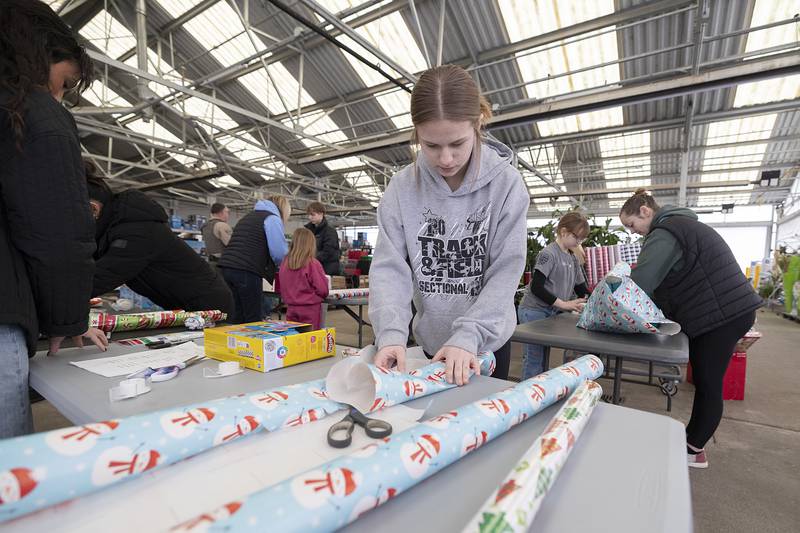 Dixon cheerleader Sofia Dula wraps up a gift Saturday, Dec. 13, 2025, at Dixon Walmart. The cheer squad volunteered to wrap the items brought in during the Shop with a Cop event.
