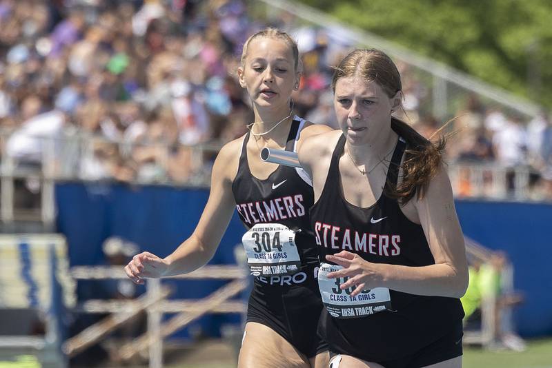 Fulton’s Grade Dykstar grabs the baton from Annaka Hackett in the 4x200 race Saturday, May 20, 2023 during the IHSA state track and field finals at Eastern Illinois University in Charleston.