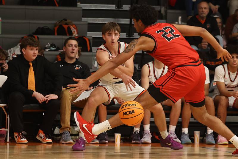 Minooka’s Kevin Bisbee passes between the pressure of Bolingbrook’s JT Pettigrew on Tuesday, Dec. 17, 2024 in Minooka.