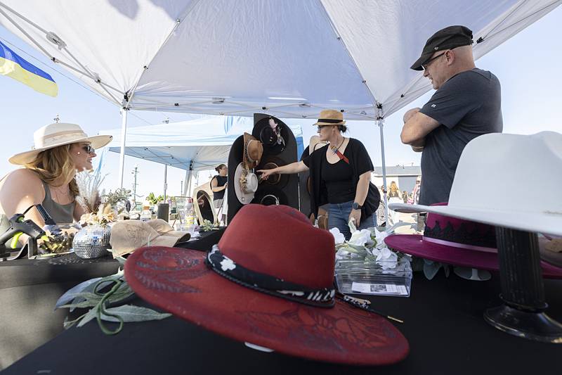 Marissa Hazell (left) of Hazel’s Headdress speaks with customers Jessie and Buddy Grett of Dixon on Wednesday, June 5, 2024, at Dixon City Market. Hazell sells unique custom-designed hats.