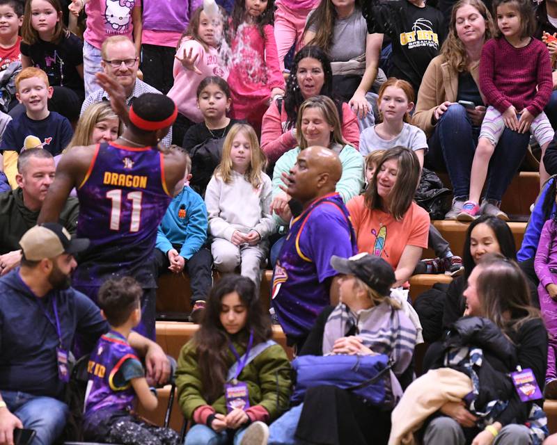 Harlem wizard player Dragon, left, has some fun with the crowd and knock a cup of water out of A-Trains hand during the game on Sunday Jan. 19, 2025, held at Downers Grove South High School.
