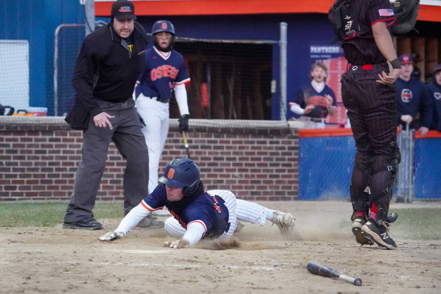 Oswego’s Jacob Fehrmann (17) slides into home scoring the go ahead run against Benet during a baseball game at Oswego High School on Tuesday, March 25, 2025.