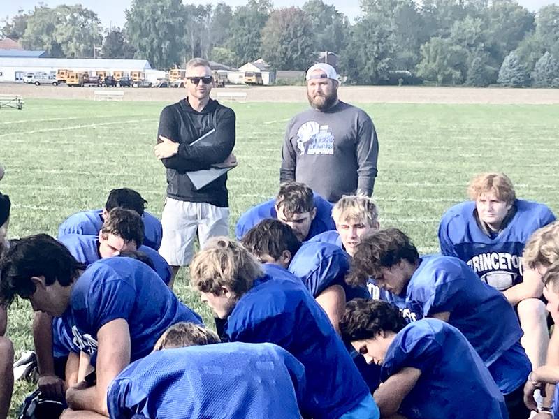 Princeton assistant coaches Patrick Smith (left) and Nathan Black look over the huddle at the end of Thursday's practice. The former Bureau Valley standouts will return home on the opposite sidelines of the Storm Friday night.