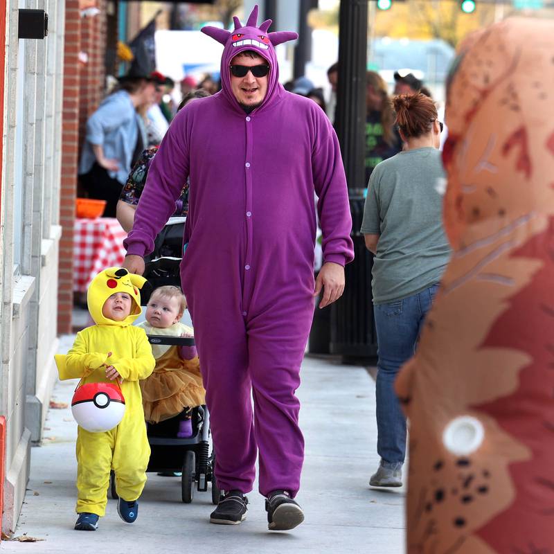 Frank Perchez and his son Aksel, 3, from DeKalb, check out a dinosaur coming towards them during the DeKalb Chamber of Commerce’s annual Spooktacular Tuesday, Oct. 29, 2024, in downtown DeKalb.
