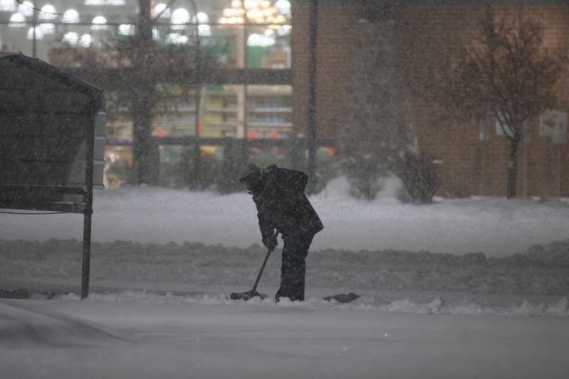 A person shovels snow around the cart return in the parking lot of Menards before they open. Wednesday, Feb. 2, 2022 in Joliet.