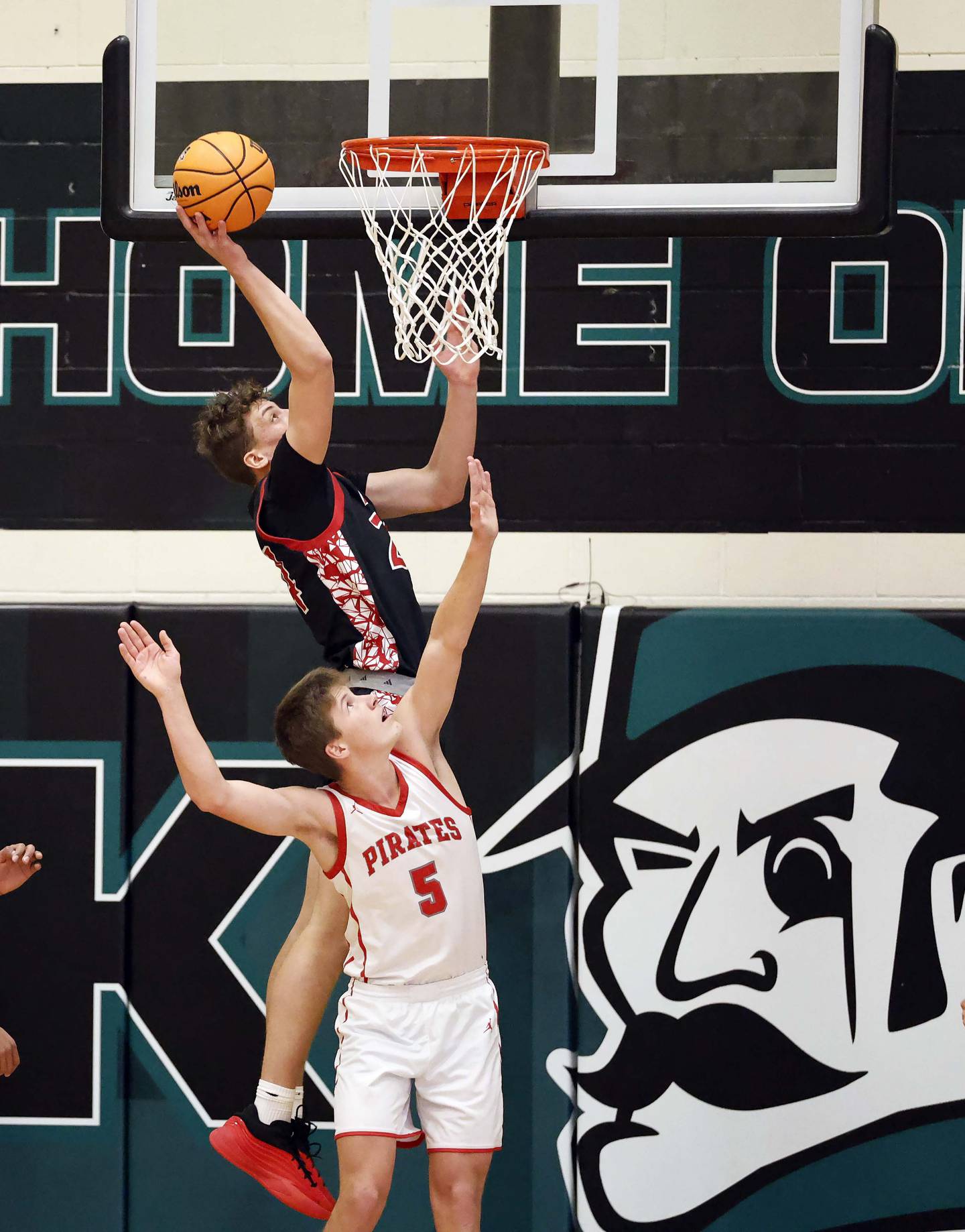 Glenbard East's Sam Walton (24) slides past Palatine's Robbie Wilcox (5) for a lay up during the 51st Jack Tosh Holiday Classic basketball tournament Monday, Dec. 29, 2025 at York High School in Elmhurst.