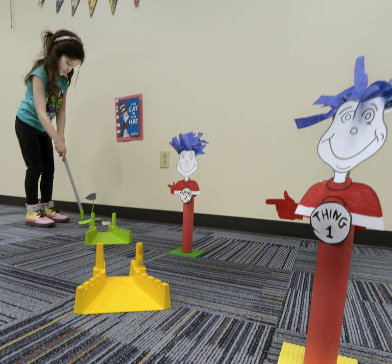 Norah Tomano plays a tough Thing 1 hole Thursday at the Reddick Library in Ottawa during a special Dr Seuss miniature golf outing to celebrate the author’s birthday.