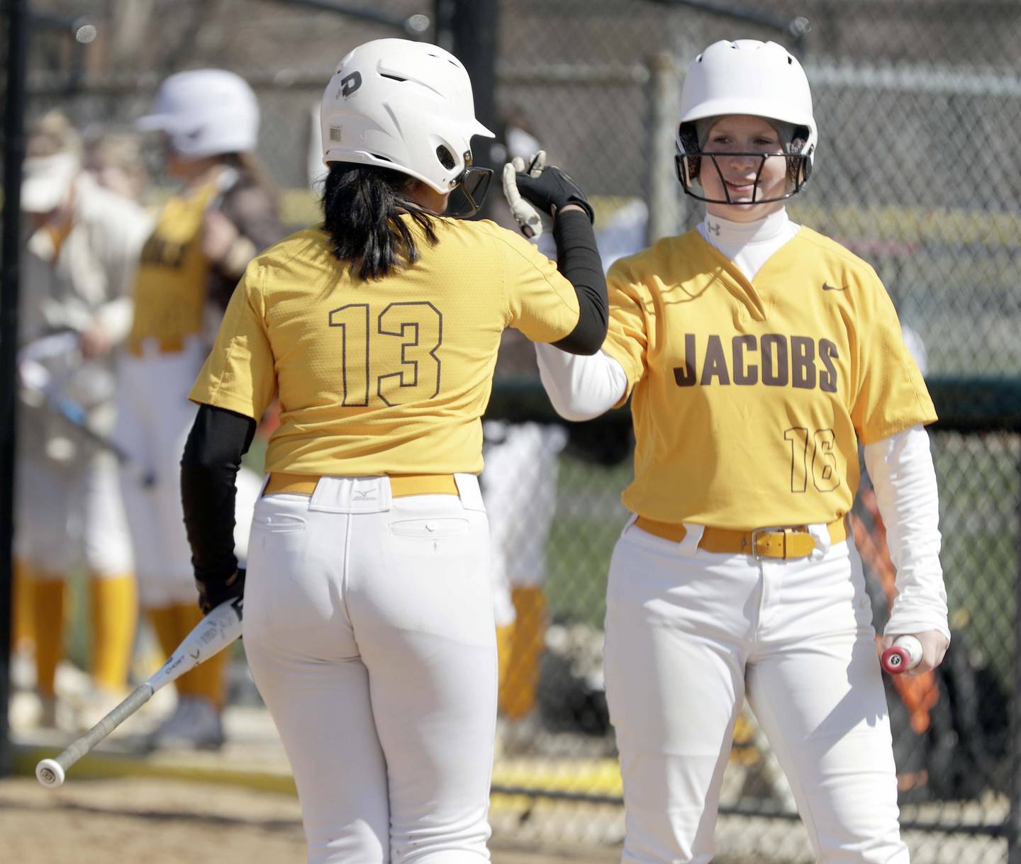 Jacobs' Arya Patel, left, is greeted at home by teammate Kaitlyn Wysong after scoring against Streamwood during the Larkin Slugfest Softball Tournament on Saturday, April 16, 2022 in Elgin.