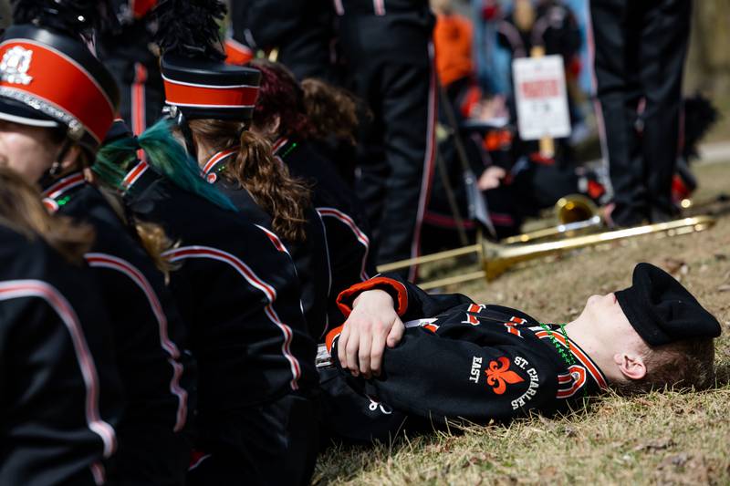 St. Charles East Band member Dean Bellizzi, 17, rests before the start of the St. Charles St. Patrick’s Parade on Main Street in St. Charles on Saturday, March 15, 2025.