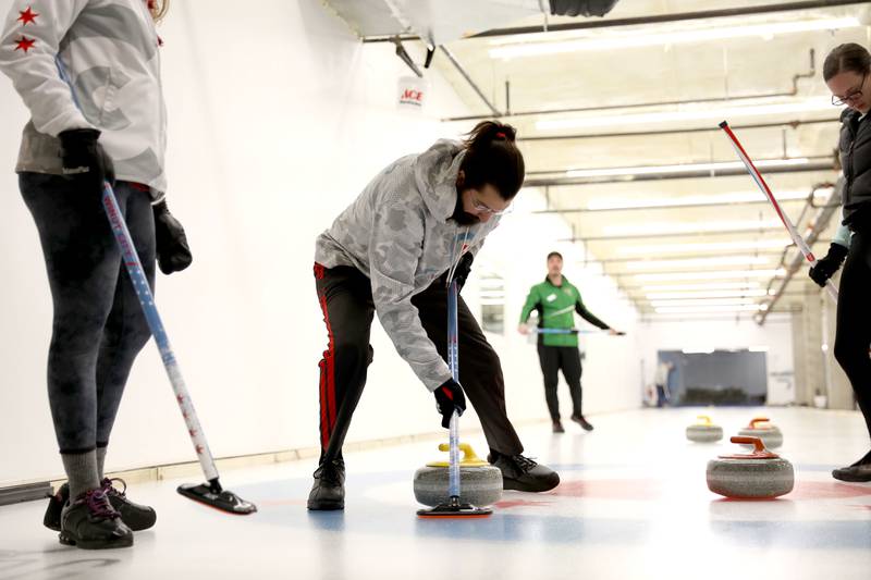 Anthony D’Arco of Lombard (center) sweeps during a drop-in game of Curling at the Windy City Curling Club in Villa Park.