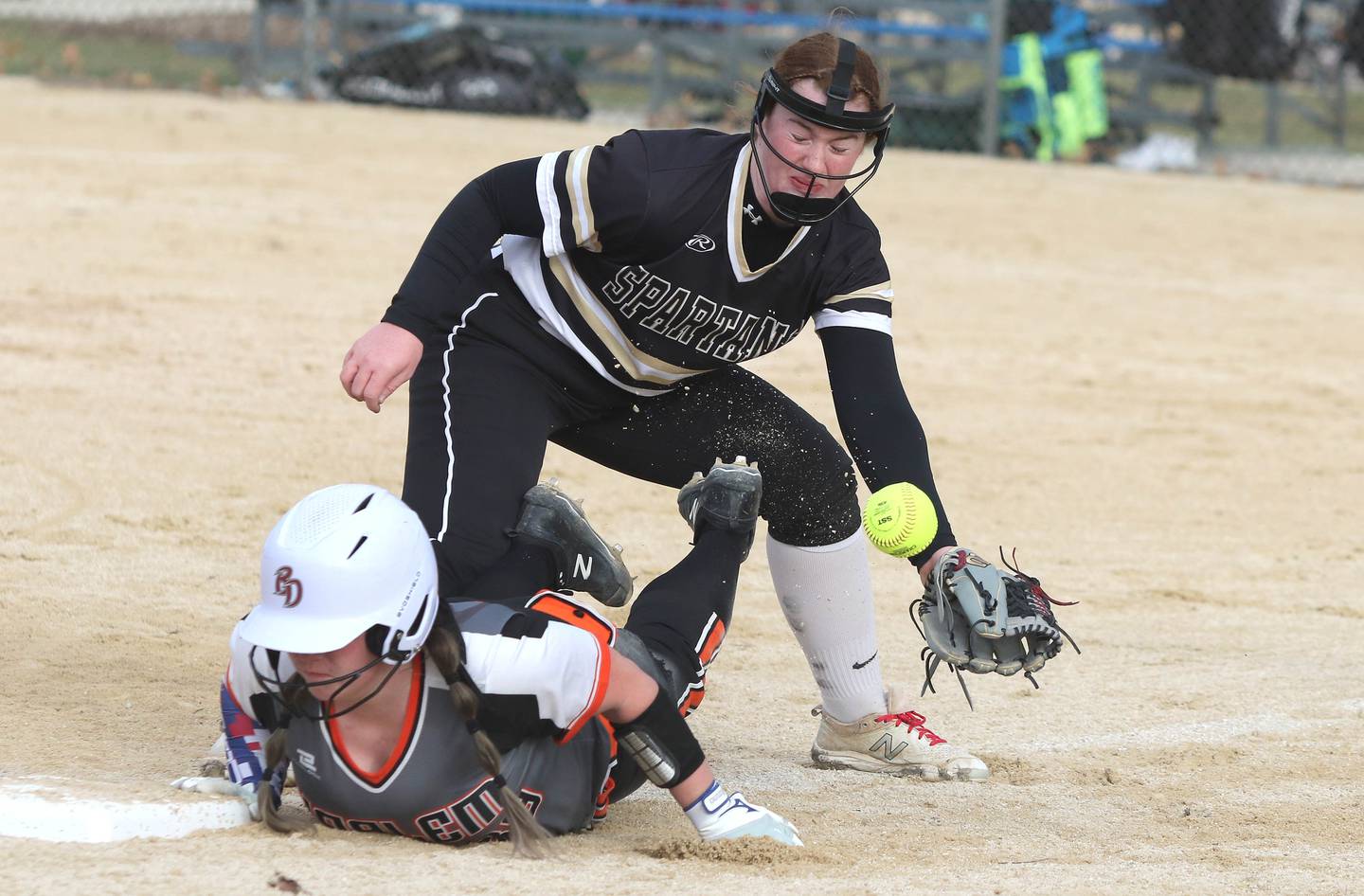 Sycamore third baseman Paige Collie takes a throw as a Harlem baserunner slides back safely during their game Friday, March 25, 2022, at the Sycamore Community Sports Complex.