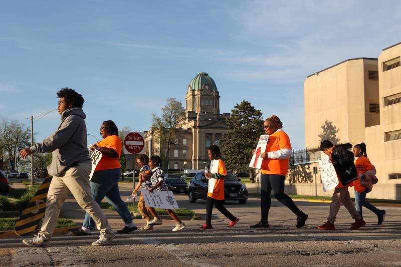 Participants carry signs voicing opposition to gun violence as they travel along Station Street in Kankakee during the 2nd annual Walk Against Gun Violence on Tuesday, April 29, 2025.