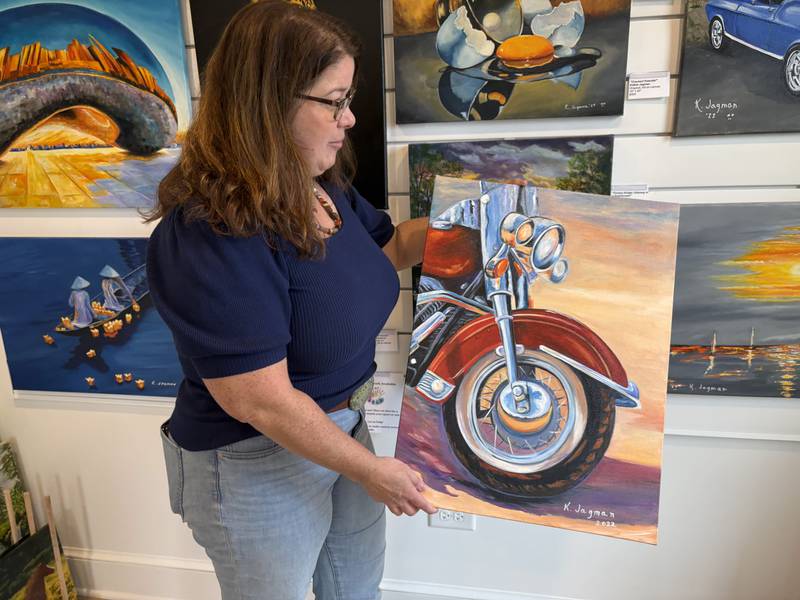 Cindy Rafkind shows off a painting by Kathie Jagman at her Huntley store, Huntley Art Hub Gallery, Oct. 28. 2025.