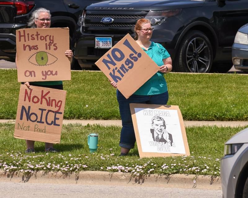 Heather Lick of Lisle, left, and Amy Svalenka of Streamwood hold signs on Saturday June 14, 2025, during the No Kings Rally held on Ogden Ave. near the Tesla dealership.
