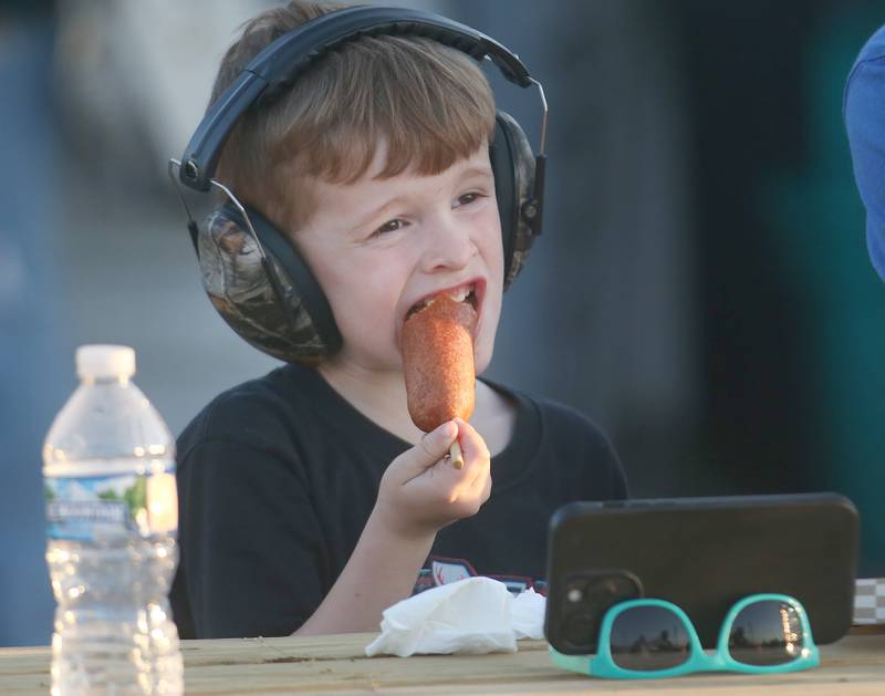 Colton Lueth of Grand Ridge, munches on a corn dog during qualifing for the season opening race on Tuesday, May 6, 2025 at La Salle Speedway. Racing returned to the venue for the first time in four years.