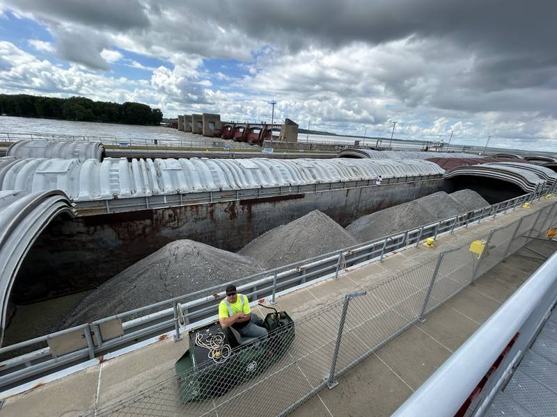 A worker at Lock & Dam 13 north of Fulton talks to visitors watching the action as a the towboat Neil N Diehl pushes barges north on the Mississippi River on Sunday, July 6, 2025.