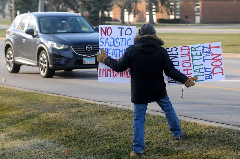 A motorist slows down to read a protester's sign Thursday, Dec. 3, 2020, during a rally aimed at persuading the McHenry County Board to cancel its contract with the U.S. Immigration Customs and Enforcement to detain immigrants in the McHenry County Jail. About 25 to 30 people protested outside the facility at 2200 N. Seminary Ave. in Woodstock.
