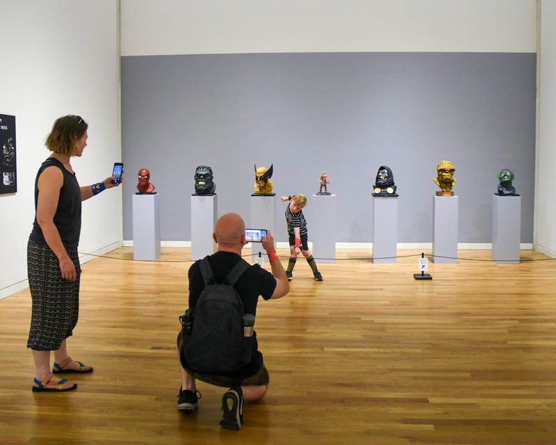 Atlas Tilson,4 years old, poses for a photo in front of sculptures of Marvel characters as his parents April Kopp and Cody Tilson take their own photos during the Marvelcity: The Art of Alex Ross  exhibit on Saturday June 24, 2023.