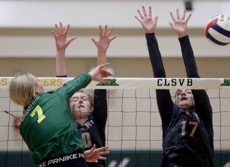Crystal Lake South’s Gabby Wire, left, hits the ball as Prairie Ridge’s Adeline Grider, center, and Mackenzie Schmidt block in varsity volleyball at Crystal Lake South Tuesday night.