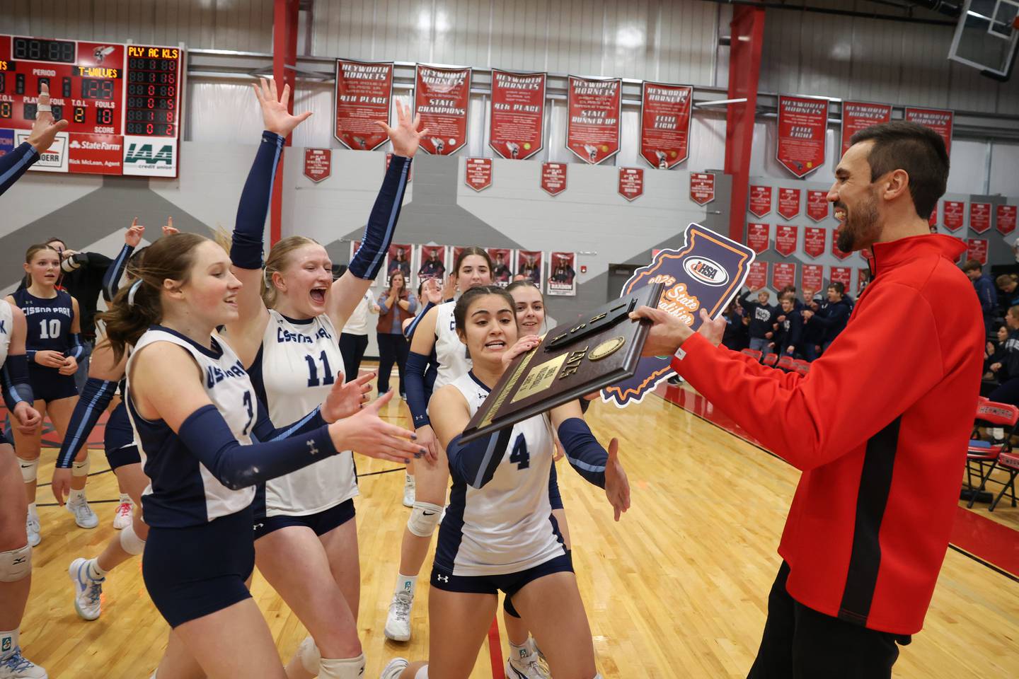 Cissna Park's Emma Malabehar (4), Sophie Duis (11) and Macy Sinn retrieve the IHSA Class 1A Heyworth Super-Sectional plaque following Timberwolves' victory in two sets, 25-22, 25-11, over Windsor/Stewardson-Strasburg on Monday, Nov. 10, 2025.