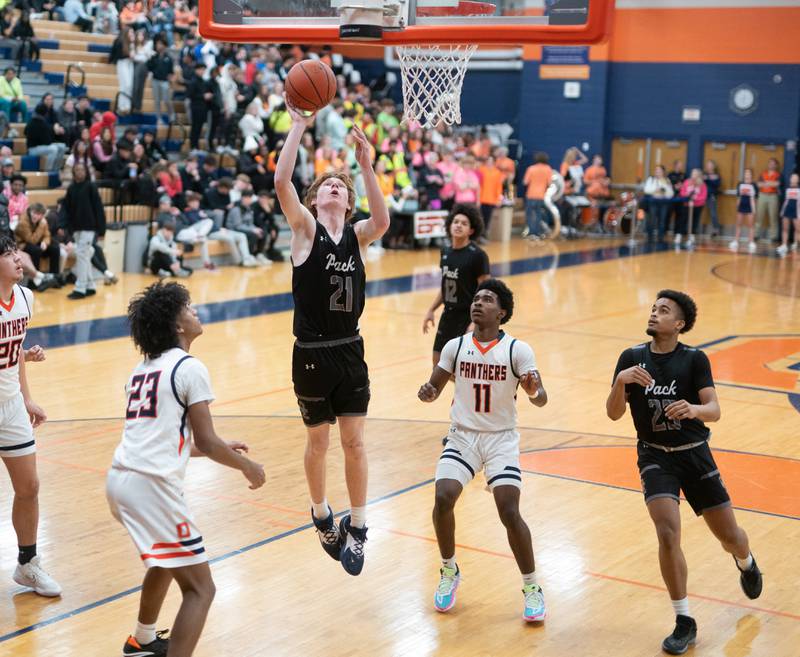 Oswego East's Andrew Pohlman (21) shoots the ball against Oswego’s Rodney Richardson (11) and Dasean Patton (23) during a basketball game at Oswego High School on Tuesday, Dec 12, 2023.
