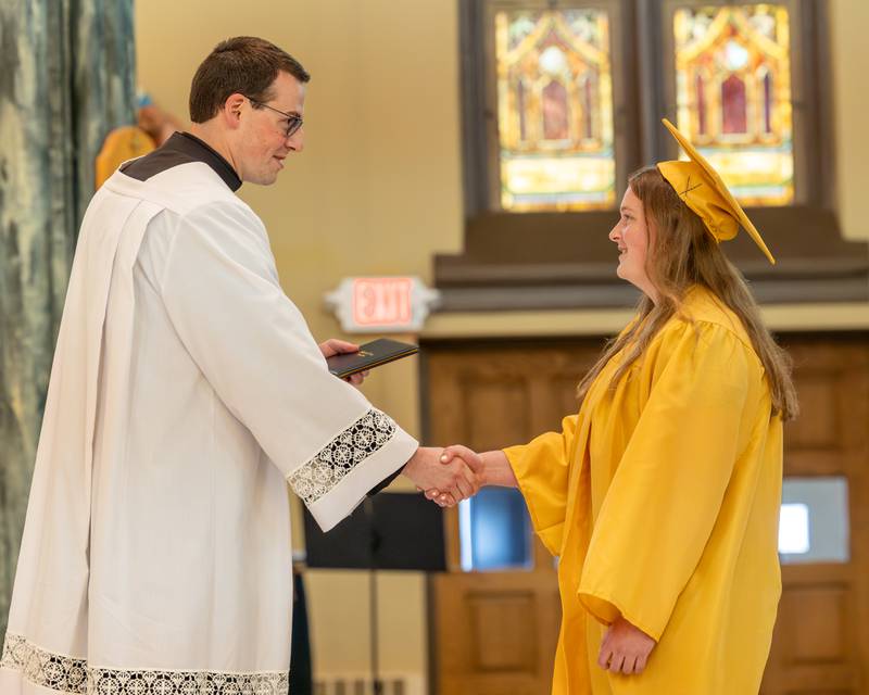 Father Nicolas Wilson hands diploma to Class of 2026 Marquette Academy Graduate during ceremony on May 24, 2026 at St. Columba Church in Ottawa.