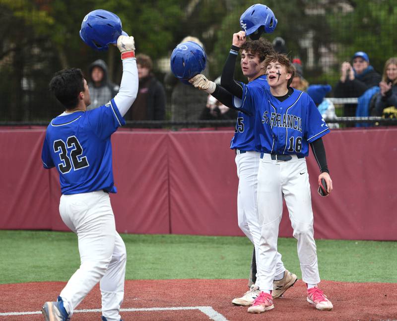 St. Francis' Rocco Tenuta (32) hit a 2-run homer and is greeted at the plate by teammates Luc Swiatek and Zach Maduzia (16) during Tuesday’s baseball game against Wheaton Academy in West Chicago.