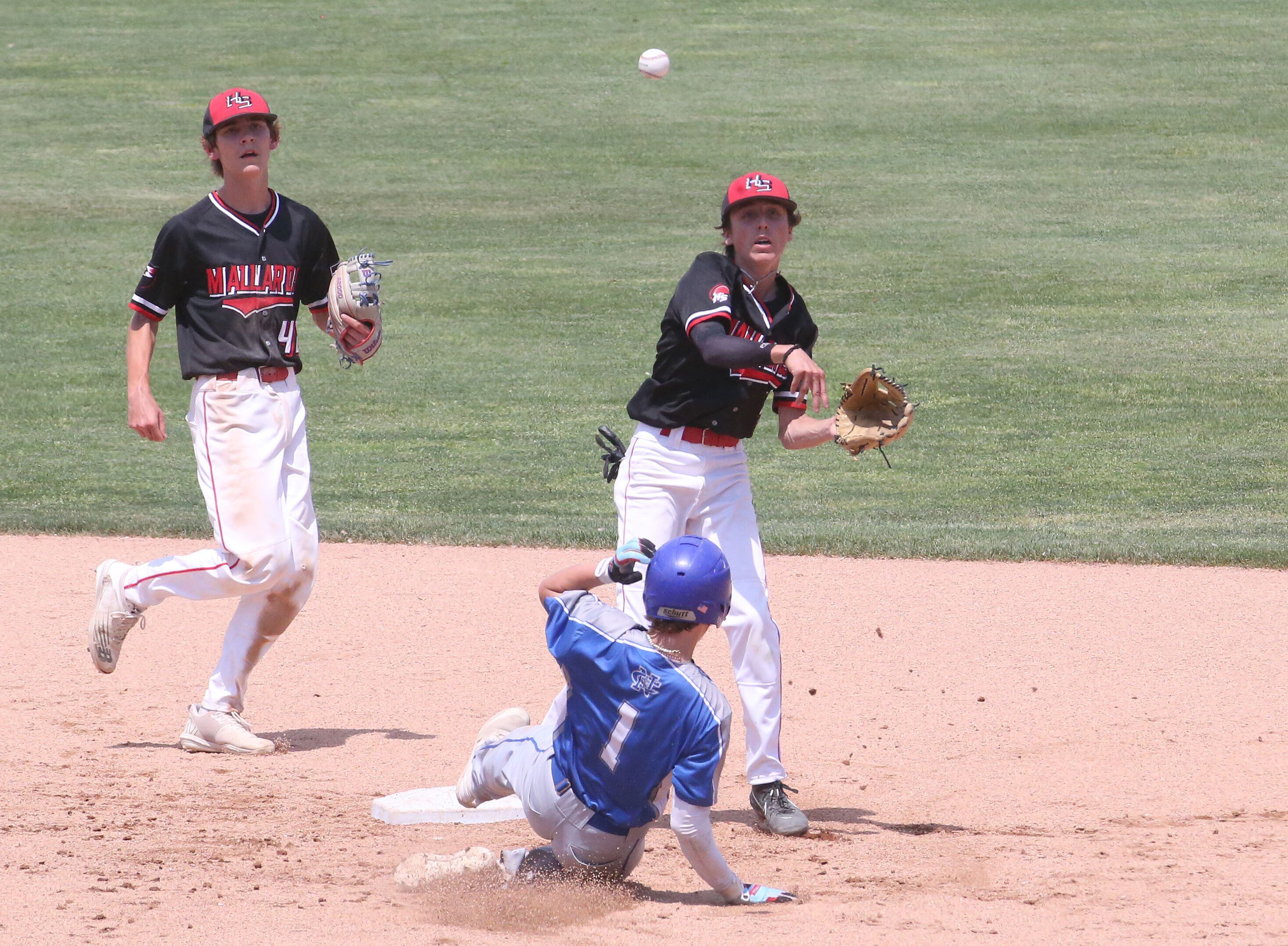 Henry-Senachwine's Carson Rowe throws to first base as teammate Teagan Williams backs him up while turning a double play on Newman's Garrett Matznick during the Class 1A State semifinal game on Friday, June 2, 2023 at Dozer Park in Peoria. 