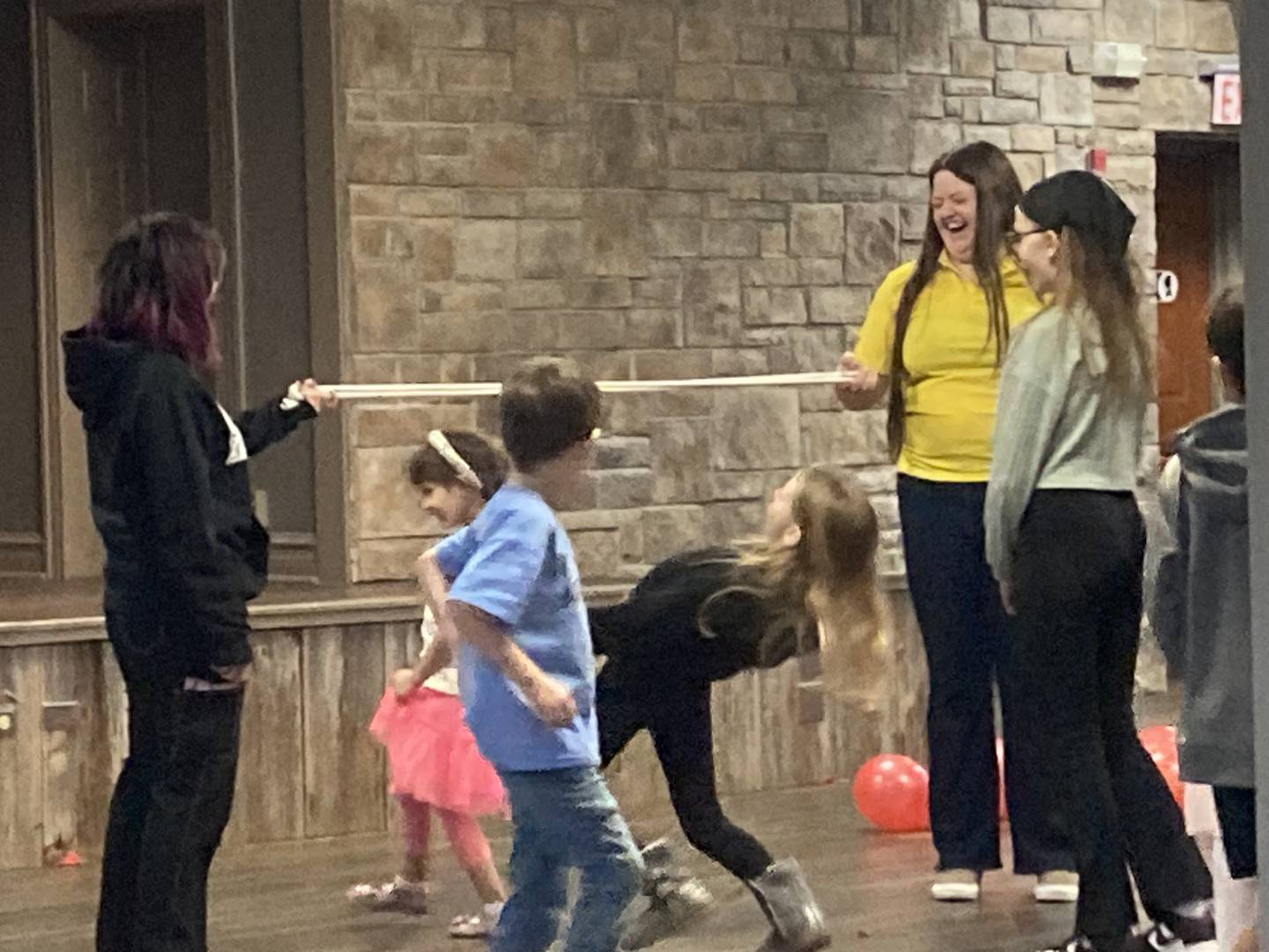 Museum employees Emily Rose and Regina Zavala hold a limbo stick for kids at the Joliet Historical Museum's Valentine's Day Party on Feb. 8, 2025.