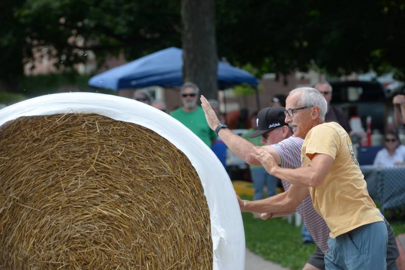 Jerry Rumple and Keith Kelly roll a large round straw bale down Wesley Avenue in Mt. Morris during the Straw Bale Race at Strawfest on Saturday, Aug. 23, 2025. The duo from Rockford placed second in this year's event.