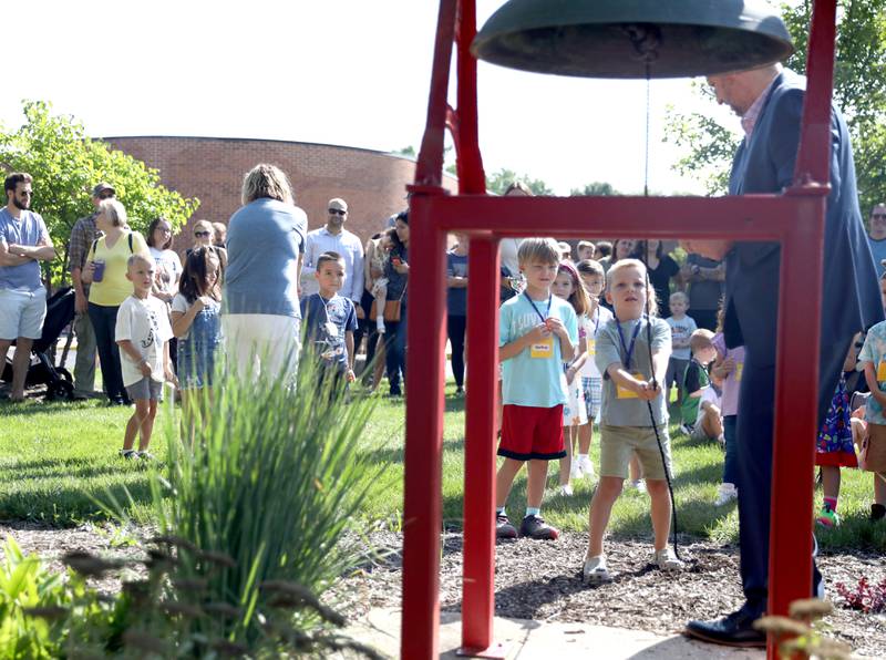 Louise White Elementary School Principal Kevin Skomer assists students as they ring the school bell on the first day of school in Batavia on Wednesday, Aug. 16, 2023.