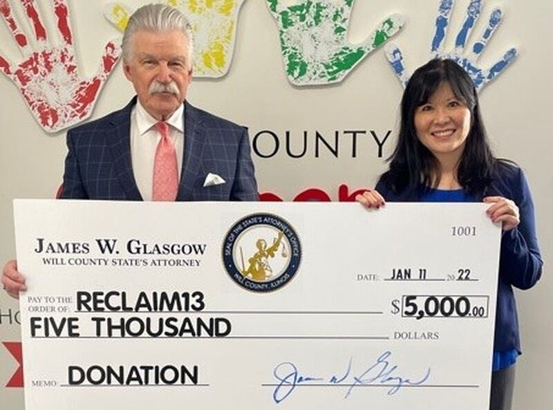 Will County State's Attorney James Glasgow (left) presents a $5,000 donation to Reclaim13, a nonprofit founded by Cassandra Ma (right).