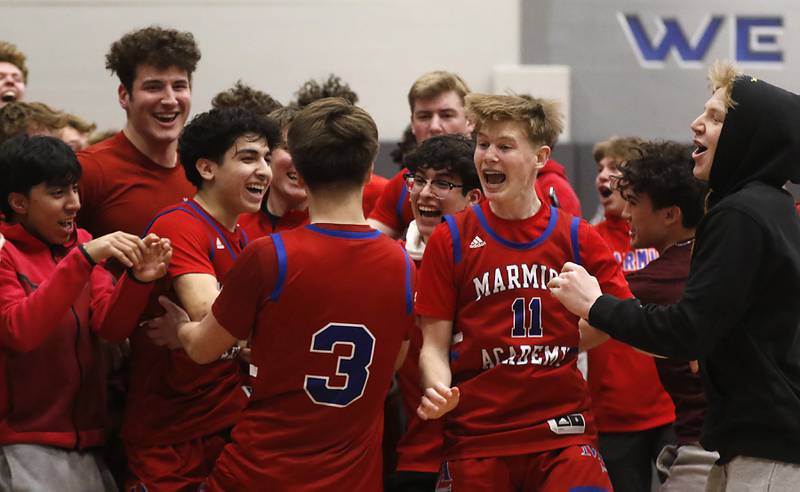 Marmion’s Collin Wainscott (center) is mugged by teammates and fans after he made a three-pointe shot in the seconds of a IHSA Class 3A Sectional boys basketball game to defeat Crystal Lake South Tuesday, Feb. 28, 2023, at Central High School in Burlington.