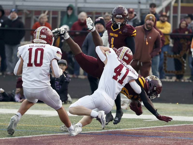 Montini's Isaac Alexander (28) dives into the undone past Morris' Keegan Kjellesvik (41) and Owen Olson (10) during the IHSA Class 4A semifinals football playoff game Saturday, Nov. 22, 2025 in Lombard.