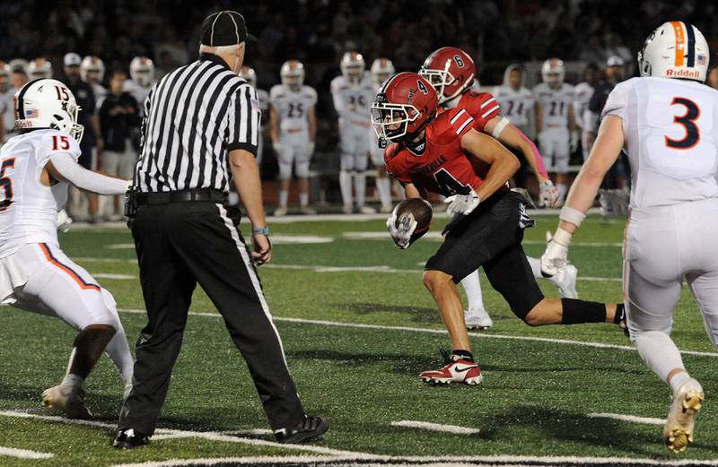 After a short reception, Yorkville receiver Eli Walton (4) finds some running room against Oswego defenders on Friday, Oct. 11, 2024, at Yorkville High School.
